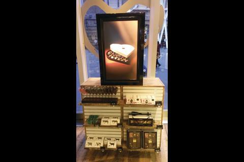 The exterior-facing side carries the message “Wink Wink” in a white font set against a rose-pink background, while on the other side there is a picture of, yes, a heart-shaped box of chocolates.